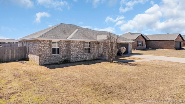 view of front of home with brick siding, roof with shingles, an attached garage, fence, and driveway