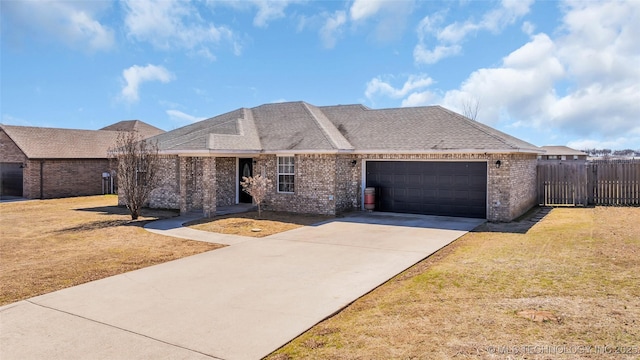 view of front of property featuring a garage, brick siding, fence, driveway, and a front lawn