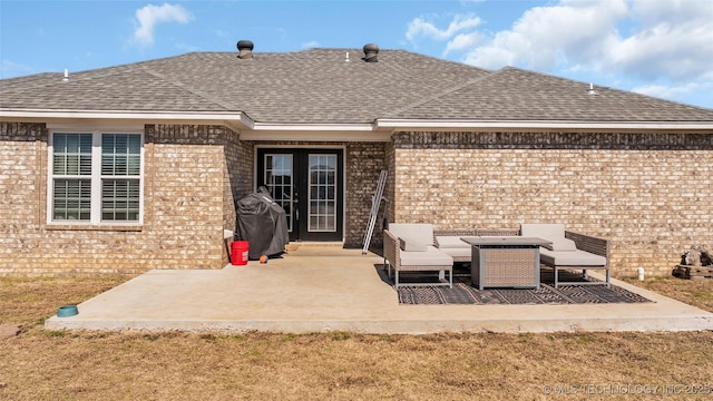 rear view of property with a patio, a shingled roof, and brick siding