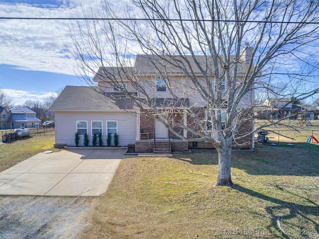 view of front facade featuring a shingled roof, brick siding, fence, and a front lawn