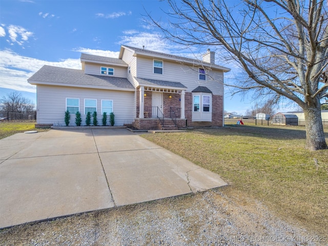 traditional-style home with brick siding, a chimney, fence, driveway, and a front lawn