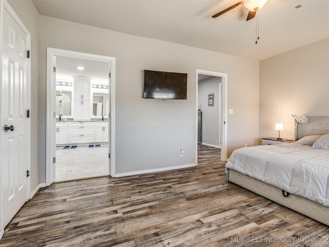 bedroom with a ceiling fan, connected bathroom, baseboards, and wood finished floors