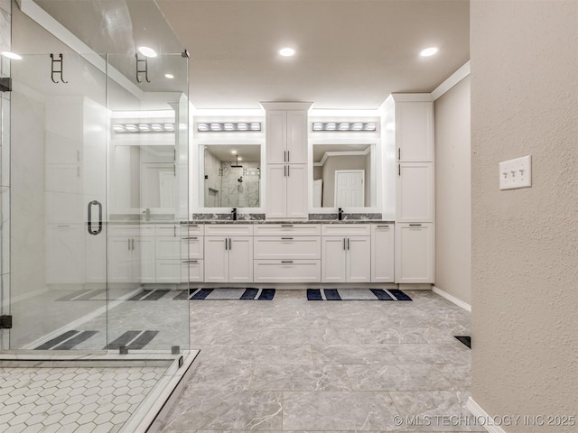 bathroom featuring a textured wall, a stall shower, a sink, and double vanity