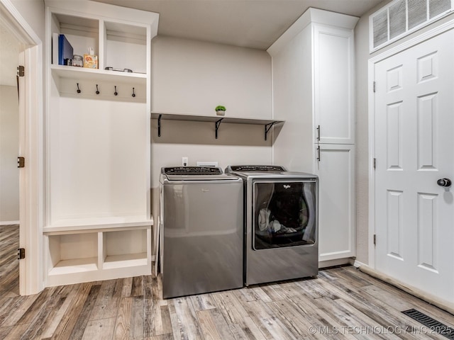 clothes washing area with cabinet space, visible vents, light wood finished floors, and separate washer and dryer