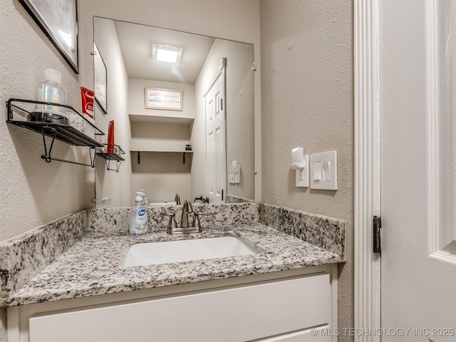 bathroom with a textured wall and vanity