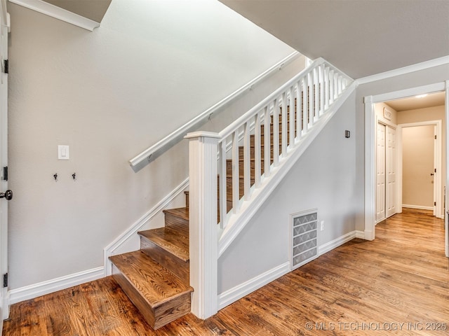 stairway with visible vents, baseboards, and wood finished floors