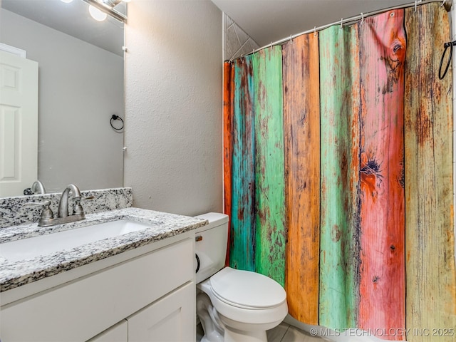 full bath featuring toilet, a textured wall, a shower with shower curtain, and vanity