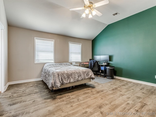 bedroom featuring ceiling fan, light wood-style flooring, visible vents, baseboards, and vaulted ceiling