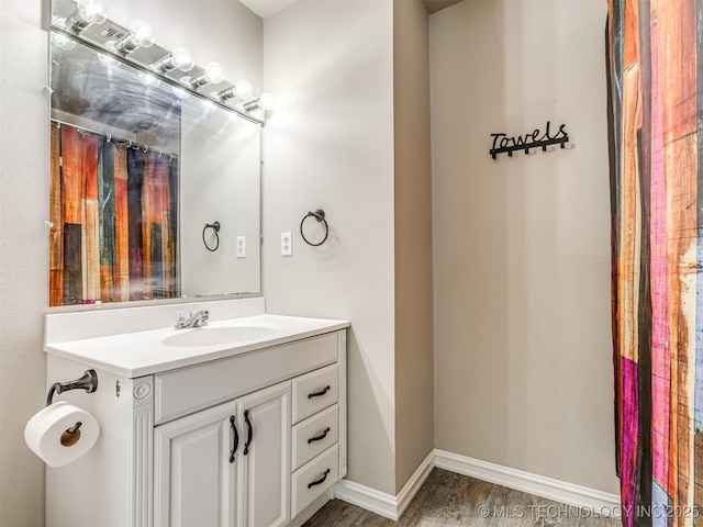 bathroom featuring wood finished floors, vanity, and baseboards