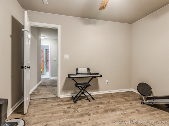 exercise area featuring ceiling fan, light wood-type flooring, and baseboards