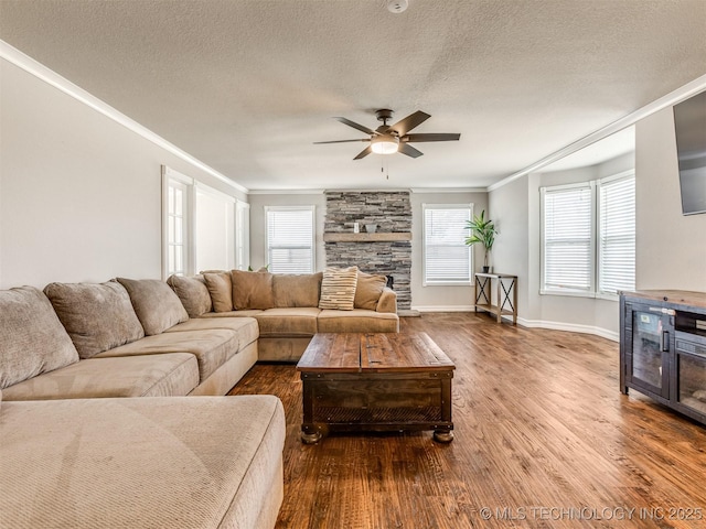 living area with ornamental molding, a ceiling fan, a textured ceiling, and wood finished floors