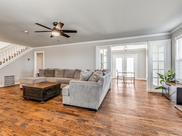 living area with plenty of natural light, dark wood finished floors, stairway, ornamental molding, and french doors