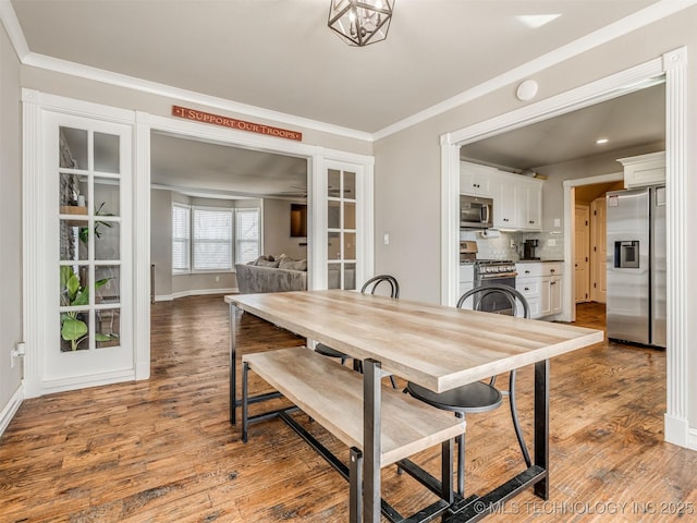 dining area featuring baseboards, ornamental molding, and wood finished floors