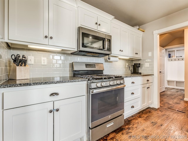 kitchen featuring stainless steel appliances, dark wood-style flooring, visible vents, white cabinetry, and dark stone counters