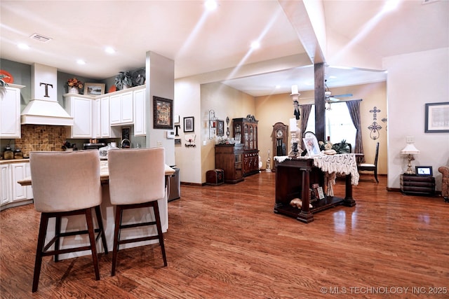 kitchen with dark wood-style flooring, a kitchen bar, visible vents, and white cabinets