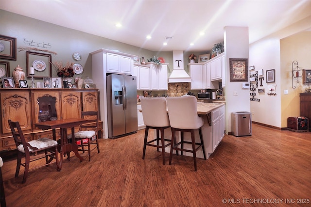 kitchen featuring dark wood finished floors, a kitchen island, appliances with stainless steel finishes, a breakfast bar, and white cabinetry