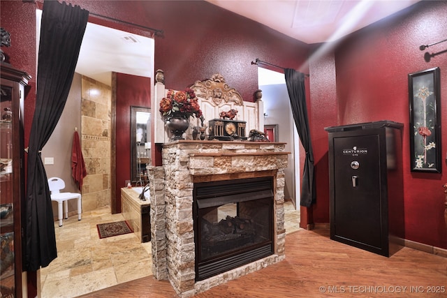 interior space featuring light wood-style floors, a textured wall, a fireplace, and baseboards