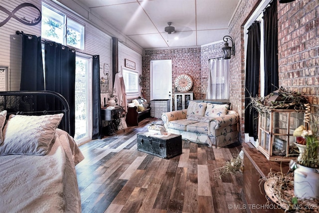 bedroom featuring brick wall and wood finished floors