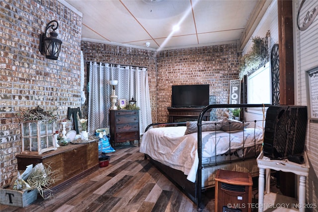 bedroom featuring brick wall and wood finished floors