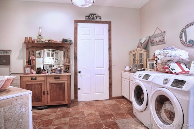 laundry room featuring stone finish flooring, washing machine and dryer, and cabinet space