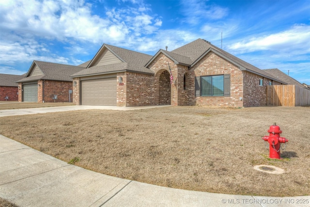 view of front of house featuring concrete driveway, brick siding, fence, and an attached garage