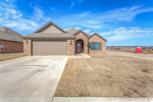 ranch-style house featuring an attached garage, brick siding, a shingled roof, driveway, and a front lawn