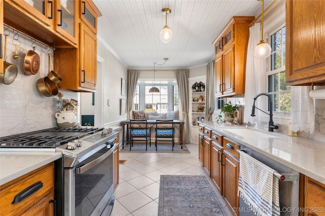 kitchen with gas stove, brown cabinets, a sink, and dishwasher