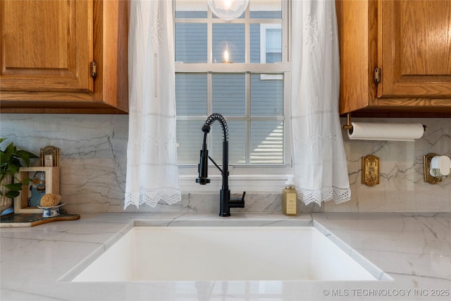 room details with brown cabinets, a sink, and backsplash