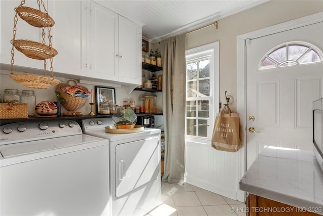 washroom with a wealth of natural light, cabinet space, washing machine and clothes dryer, and light tile patterned floors