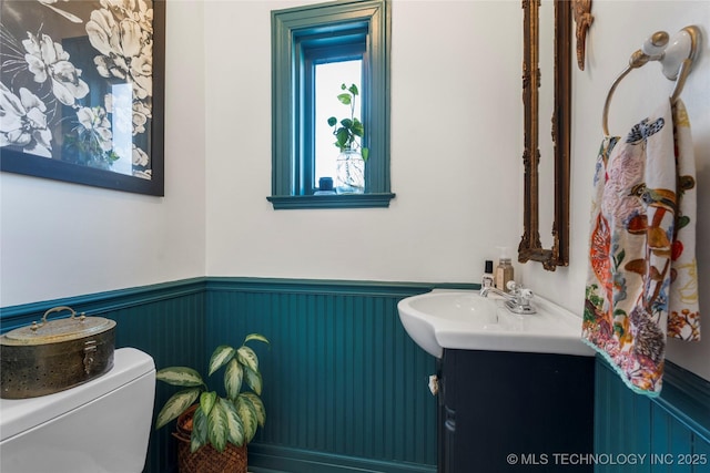 bathroom with a wainscoted wall, vanity, and toilet