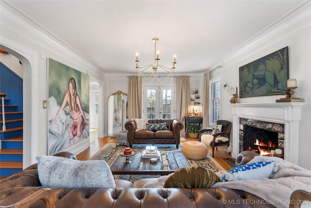 living room with ornamental molding, wood finished floors, stairs, french doors, and a fireplace