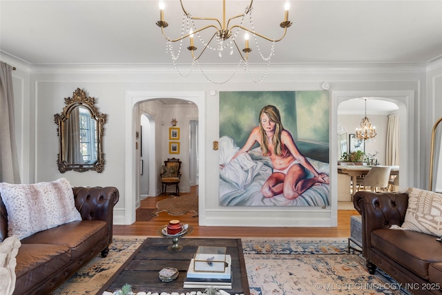 living area featuring arched walkways, wood finished floors, a chandelier, and crown molding