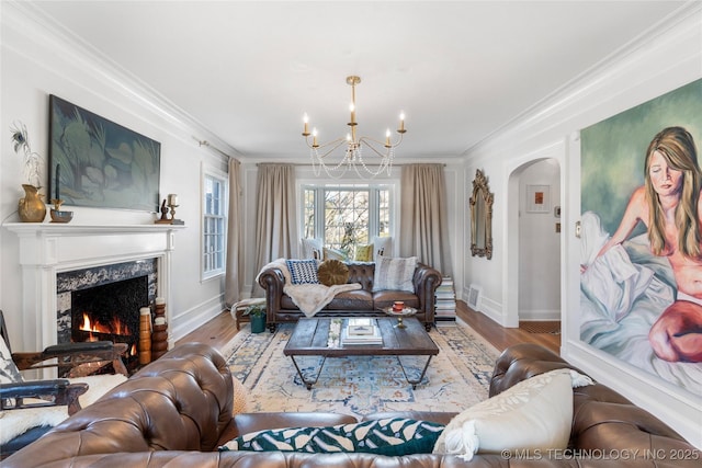 living area featuring arched walkways, wood finished floors, crown molding, and a premium fireplace