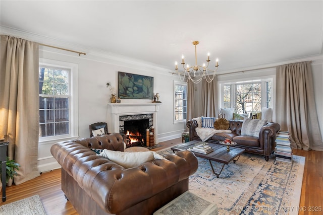 living area featuring ornamental molding, light wood-style floors, a healthy amount of sunlight, and a fireplace