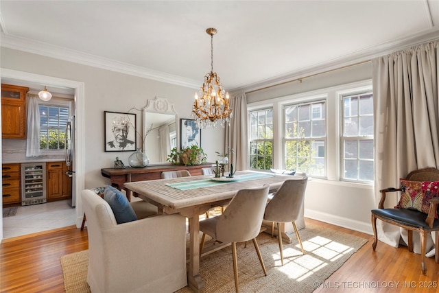 dining area featuring light wood-type flooring, beverage cooler, baseboards, and crown molding