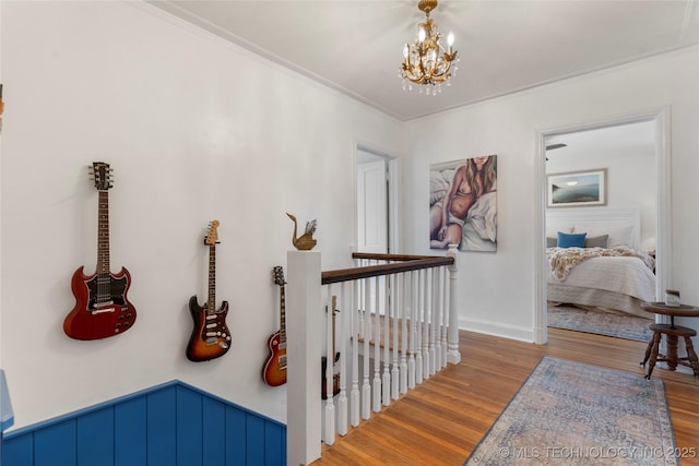 hall with ornamental molding, a notable chandelier, an upstairs landing, and wood finished floors