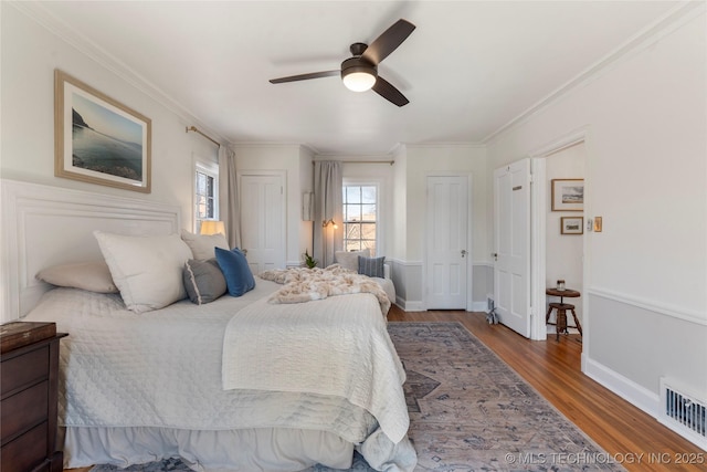 bedroom featuring baseboards, visible vents, a ceiling fan, wood finished floors, and crown molding