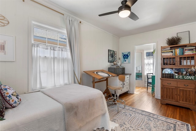 bedroom featuring wood finished floors, a ceiling fan, and crown molding