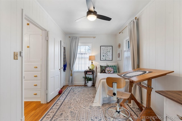 living area with ornamental molding, light wood finished floors, and a ceiling fan