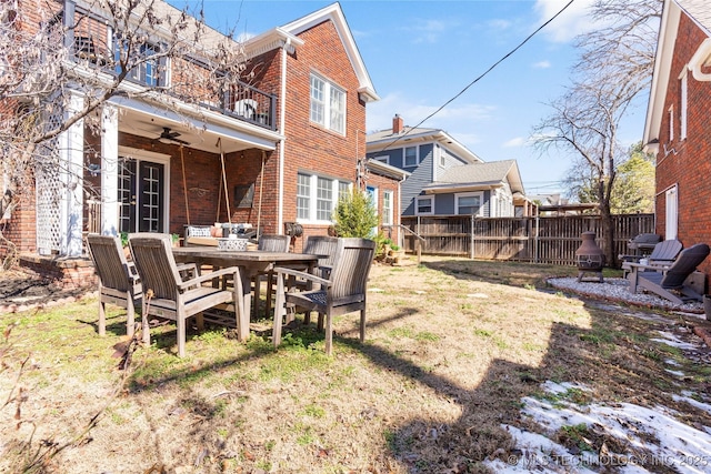 view of yard with a patio, a balcony, fence, a ceiling fan, and french doors