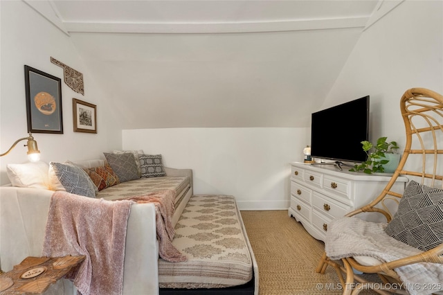 living area with baseboards, vaulted ceiling, and light colored carpet