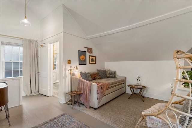 living area with baseboards, vaulted ceiling, and wood finished floors