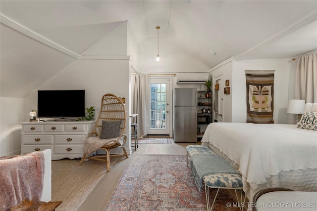 bedroom with access to exterior, vaulted ceiling, an AC wall unit, light wood-type flooring, and freestanding refrigerator