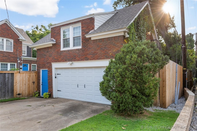 view of front of house with brick siding, driveway, fence, and roof with shingles