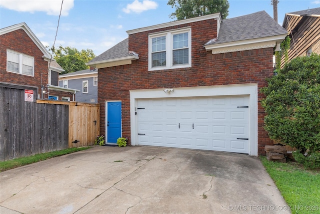 view of front facade featuring a garage, brick siding, fence, driveway, and roof with shingles