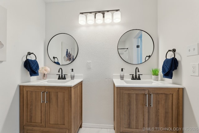 full bathroom with two vanities, a sink, and baseboards