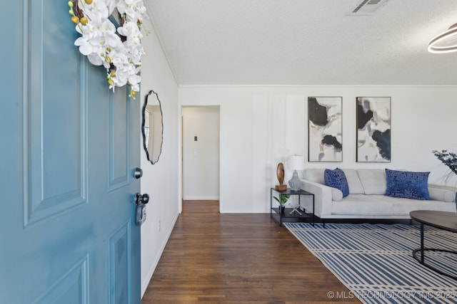 foyer entrance with visible vents, a textured ceiling, baseboards, and wood finished floors