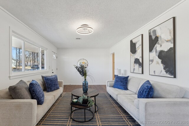 living area featuring visible vents, ornamental molding, and wood finished floors