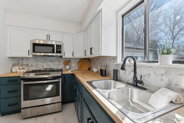 kitchen featuring a sink, stainless steel appliances, wood counters, and white cabinetry