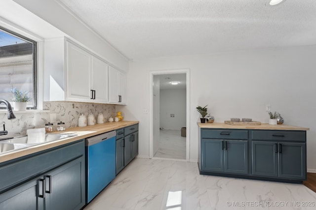 kitchen with white cabinets, dishwasher, backsplash, marble finish floor, and a sink